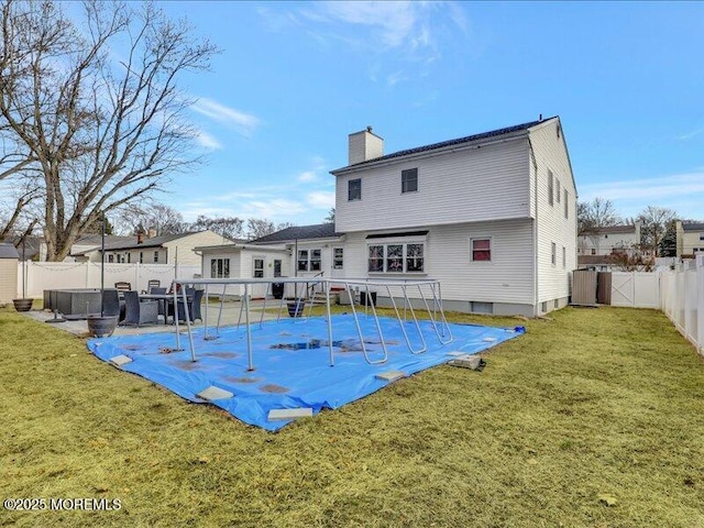 rear view of property with a yard, a fenced backyard, a patio, and a chimney