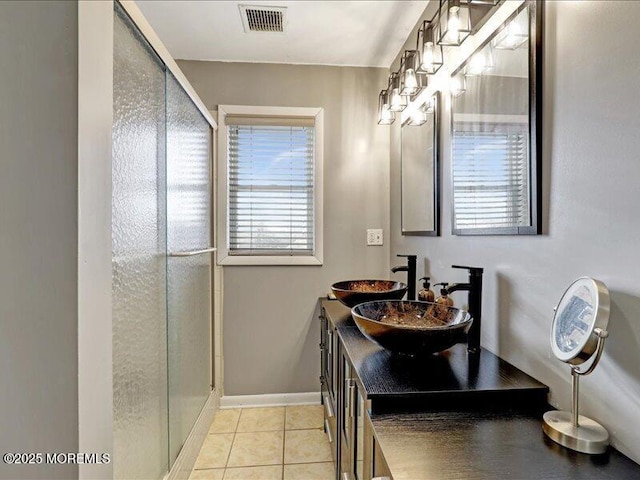 full bath with visible vents, a stall shower, a sink, baseboards, and tile patterned floors