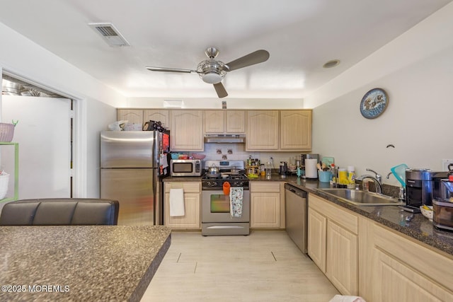 kitchen featuring light brown cabinets, under cabinet range hood, stainless steel appliances, a sink, and visible vents