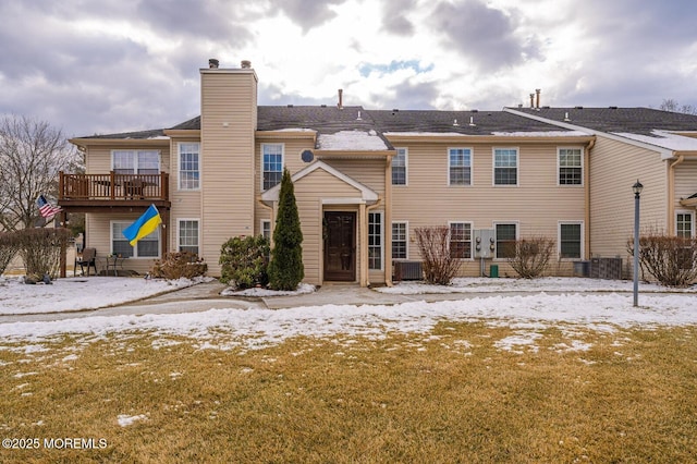 snow covered property with a chimney and cooling unit