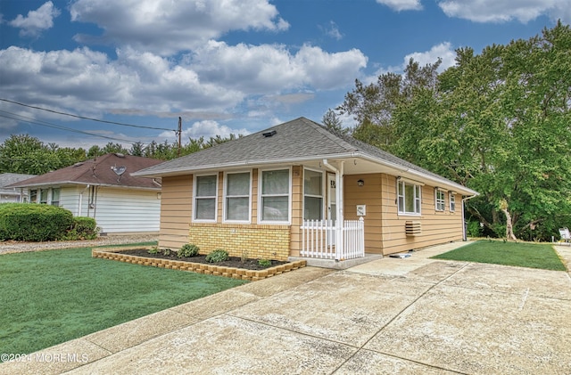 view of front of property featuring brick siding, a shingled roof, concrete driveway, and a front yard