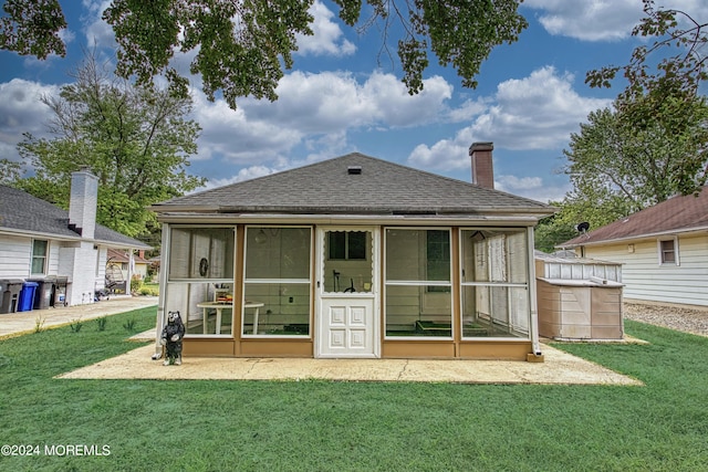 rear view of house featuring a yard, roof with shingles, and a sunroom