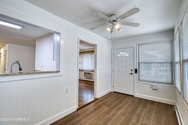 foyer entrance with dark wood-style floors, an AC wall unit, baseboard heating, and plenty of natural light