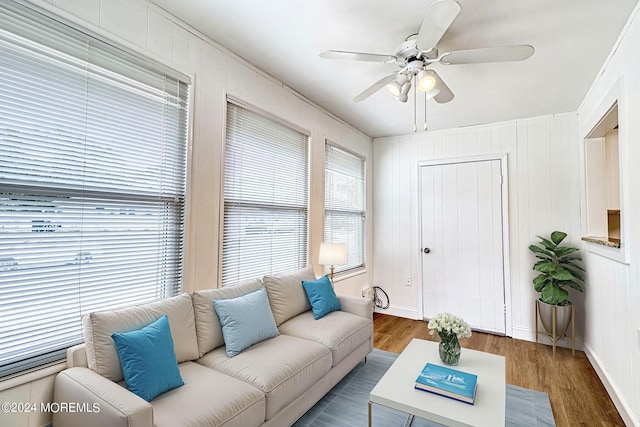 living area with a ceiling fan, baseboards, and wood finished floors