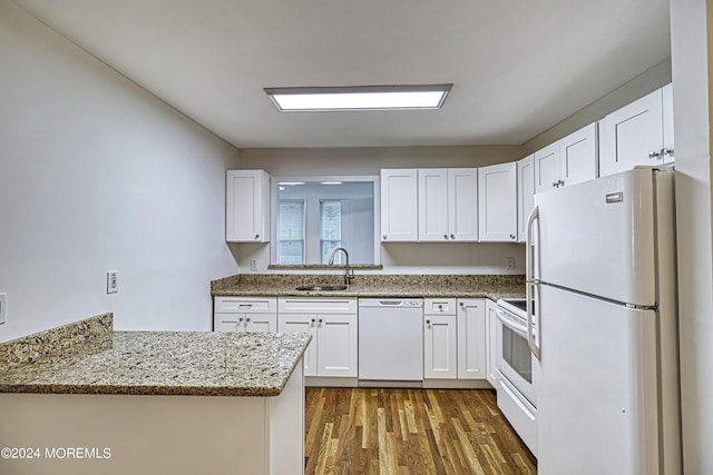 kitchen with light stone counters, dark wood-type flooring, white cabinets, a sink, and white appliances