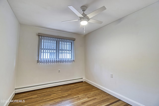 empty room featuring ceiling fan, baseboard heating, wood finished floors, and baseboards