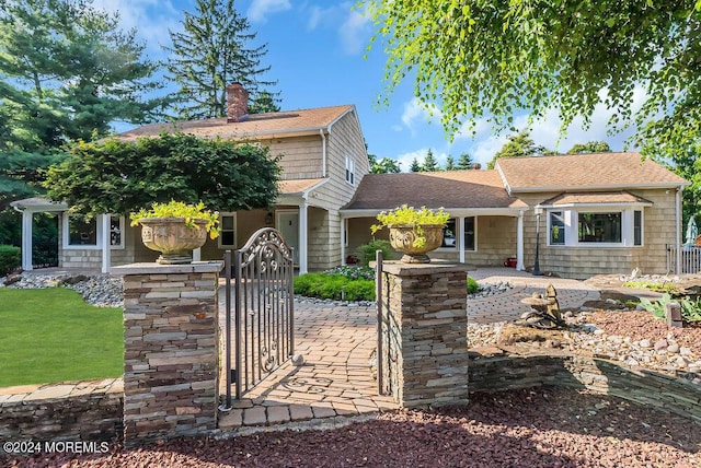 view of front of property featuring a shingled roof, a chimney, a gate, and fence