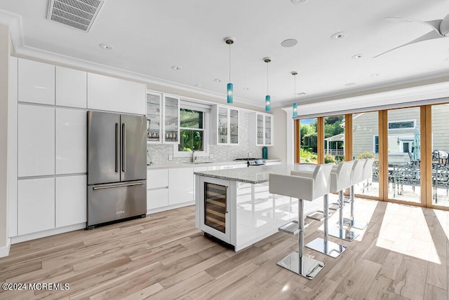 kitchen featuring high quality fridge, beverage cooler, a sink, visible vents, and crown molding