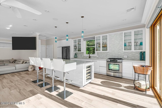 kitchen featuring visible vents, white cabinets, ornamental molding, a sink, and gas stove