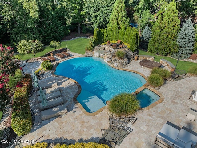 pool with a patio area, a fire pit, and a lawn