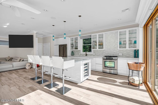 kitchen with visible vents, crown molding, stainless steel range with gas cooktop, white cabinetry, and a sink