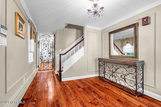 foyer entrance with a notable chandelier, crown molding, stairway, wood finished floors, and plenty of natural light