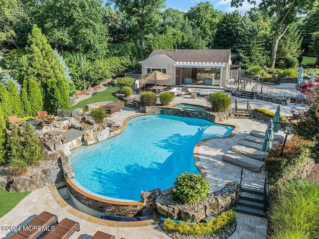 outdoor pool with an outbuilding, a storage structure, an in ground hot tub, fence, and a patio area