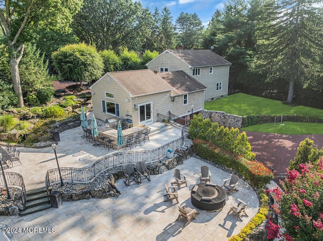 back of house with an outdoor fire pit, outdoor dining area, a shingled roof, a yard, and a patio area