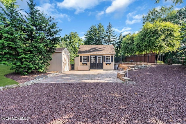 exterior space with a storage shed, roof with shingles, fence, and an outdoor structure