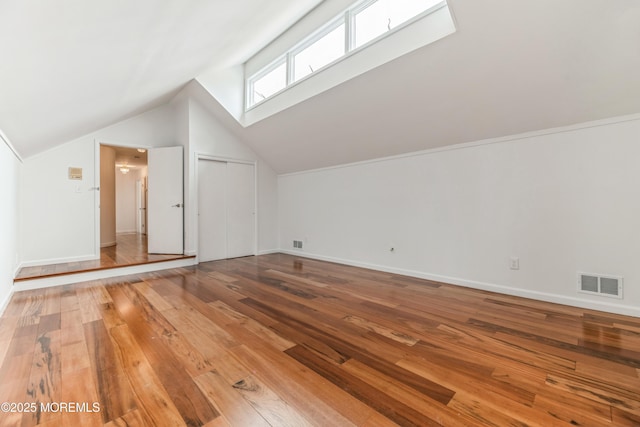 bonus room with vaulted ceiling, hardwood / wood-style flooring, visible vents, and baseboards