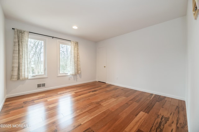 empty room featuring light wood finished floors, baseboards, and visible vents