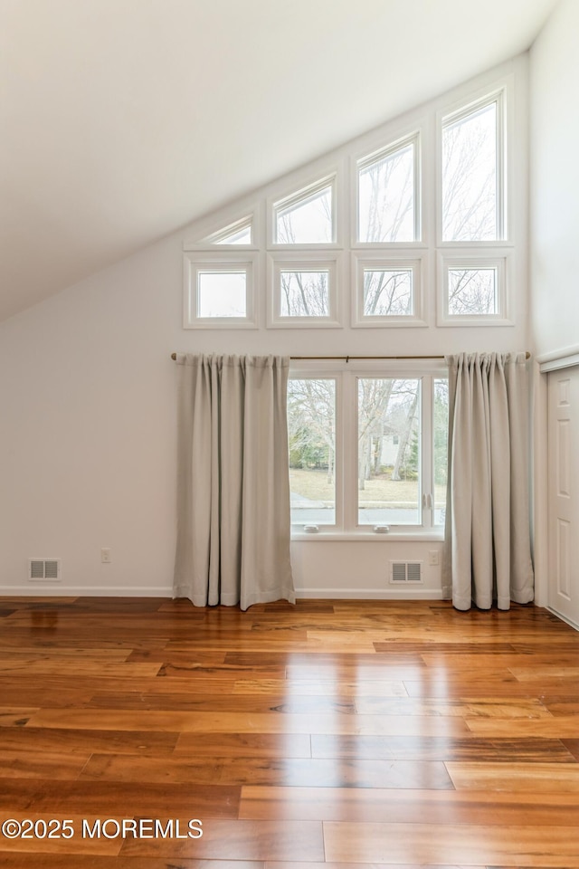 additional living space with light wood finished floors, visible vents, and baseboards