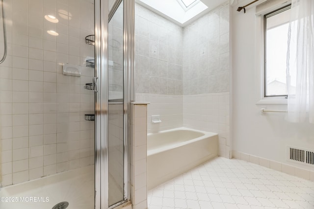 full bath featuring a garden tub, a skylight, visible vents, baseboards, and a shower stall