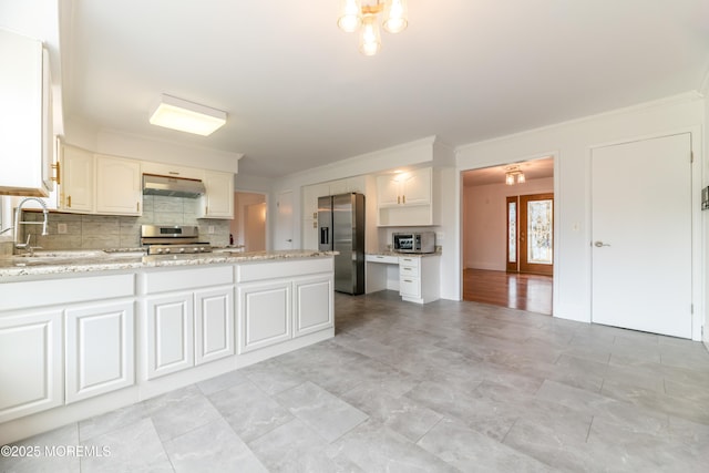 kitchen with backsplash, appliances with stainless steel finishes, a sink, a peninsula, and under cabinet range hood