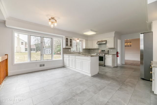 kitchen featuring visible vents, appliances with stainless steel finishes, a peninsula, under cabinet range hood, and backsplash