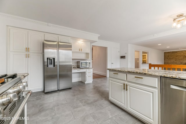 kitchen featuring appliances with stainless steel finishes, white cabinets, crown molding, and light stone countertops