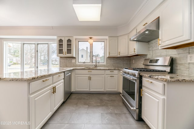 kitchen with stainless steel appliances, a wealth of natural light, decorative backsplash, a peninsula, and under cabinet range hood