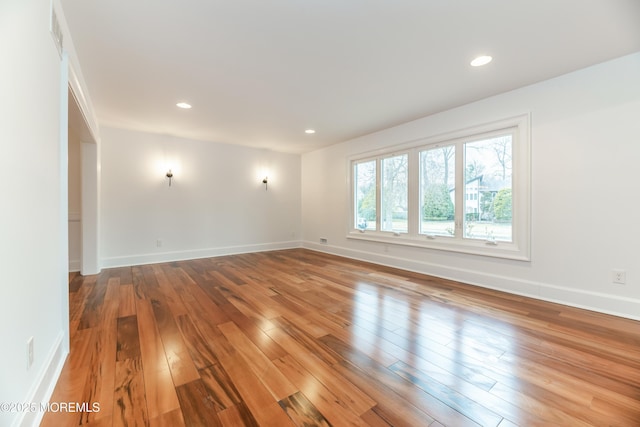 unfurnished room featuring baseboards, wood finished floors, and recessed lighting