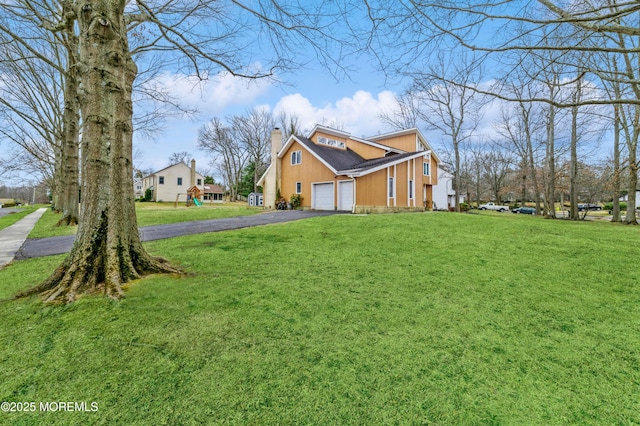 view of home's exterior featuring a chimney, aphalt driveway, and a yard