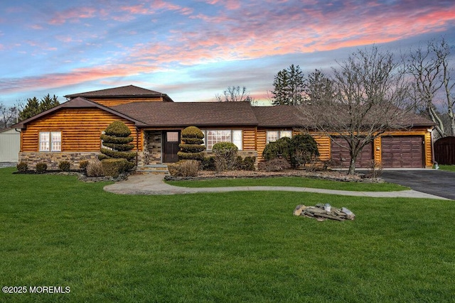 view of front of house featuring an attached garage, stone siding, aphalt driveway, and a yard