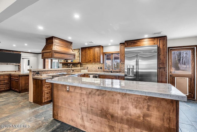 kitchen with visible vents, decorative backsplash, appliances with stainless steel finishes, premium range hood, and a peninsula