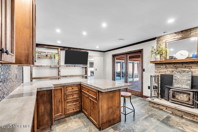 kitchen featuring stone tile floors, decorative backsplash, a peninsula, light countertops, and french doors