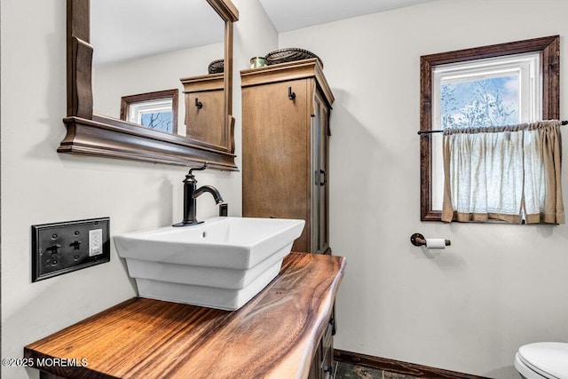 bathroom with toilet, baseboards, and vanity