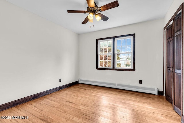 unfurnished bedroom with ceiling fan, baseboard heating, light wood-type flooring, and baseboards