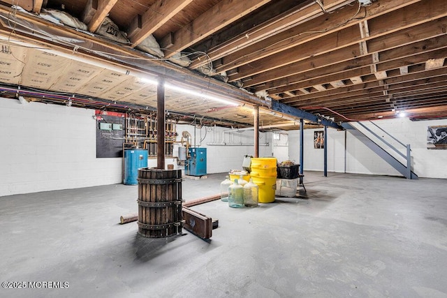 unfinished below grade area featuring water heater and concrete block wall