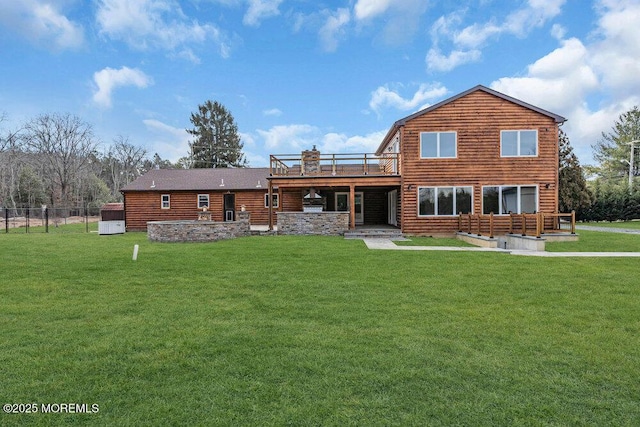 back of property featuring a lawn, a wooden deck, and fence