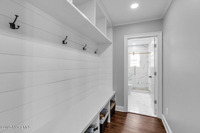 mudroom with dark wood-style flooring, crown molding, and baseboards