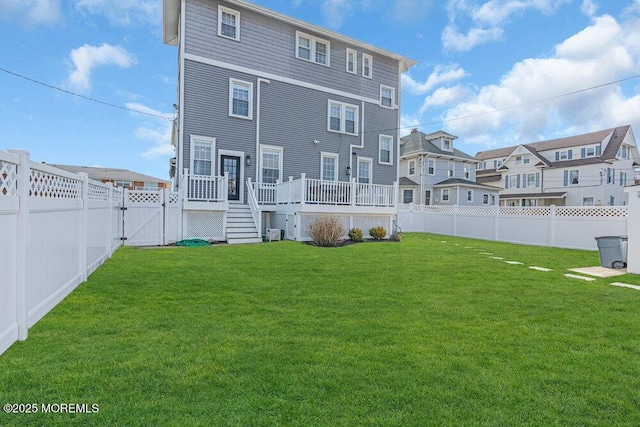 rear view of property with a yard, a fenced backyard, a gate, and a wooden deck