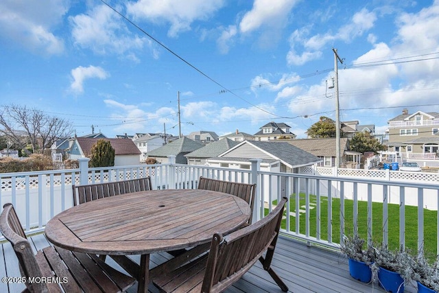 wooden deck featuring a yard, outdoor dining area, fence, and a residential view