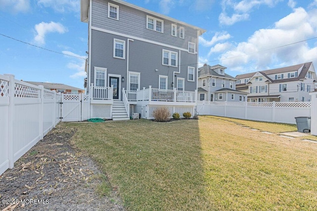 back of property featuring a gate, a fenced backyard, a lawn, and a wooden deck