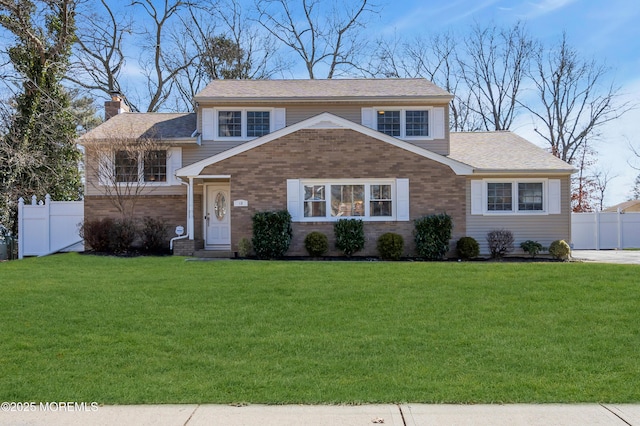 view of front of house with brick siding, a chimney, a front yard, and fence