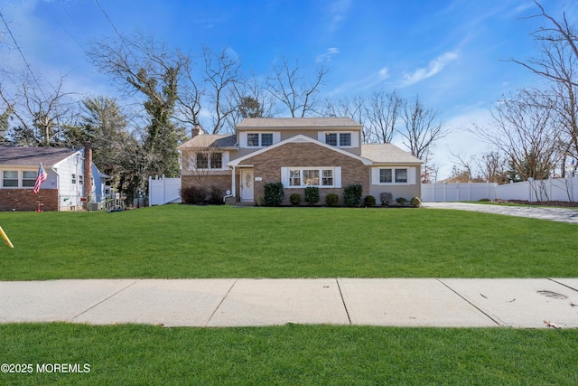 view of front facade featuring brick siding, a front lawn, and fence