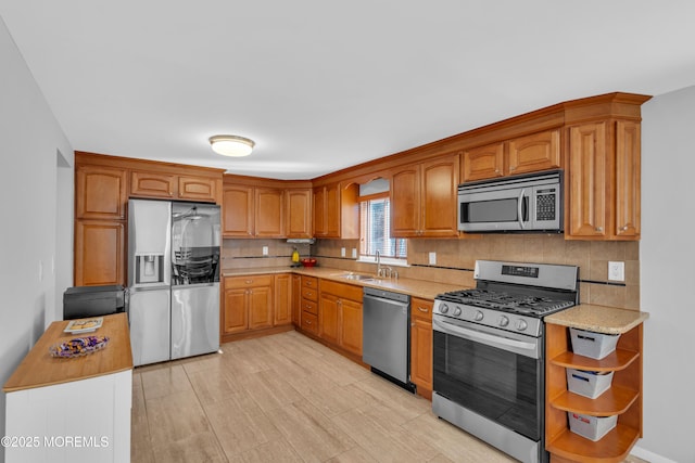 kitchen featuring a sink, decorative backsplash, brown cabinets, appliances with stainless steel finishes, and open shelves