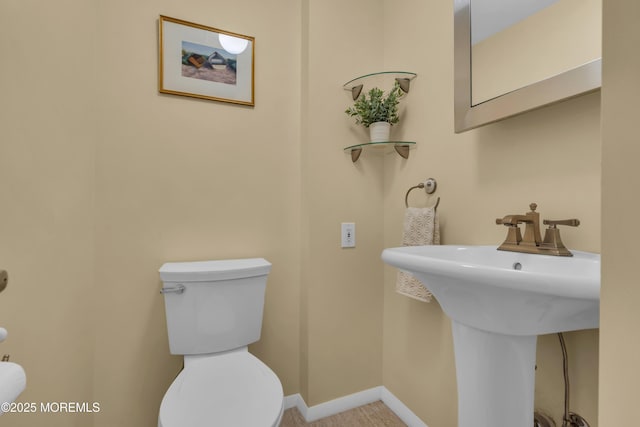 half bathroom featuring a sink, baseboards, and toilet