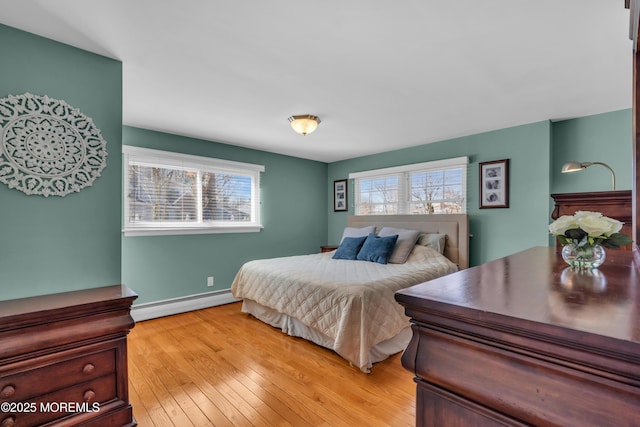 bedroom with baseboard heating, baseboards, and light wood-style floors