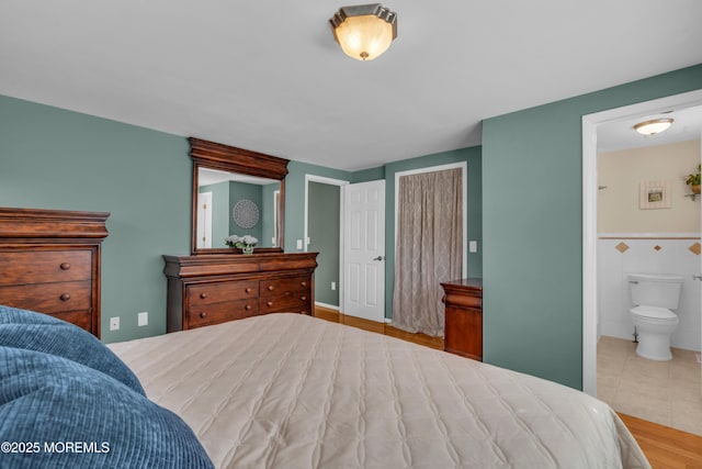 tiled bedroom featuring connected bathroom and tile walls