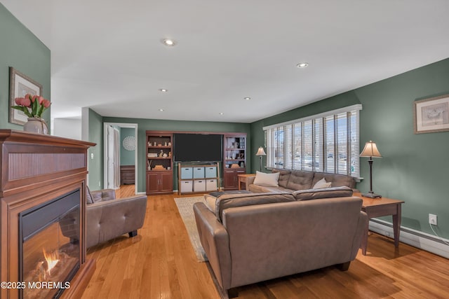 living area featuring recessed lighting, light wood-type flooring, a lit fireplace, and a baseboard radiator