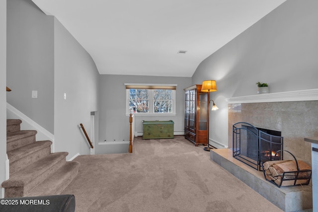 carpeted living area with visible vents, baseboards, lofted ceiling, a premium fireplace, and a baseboard radiator