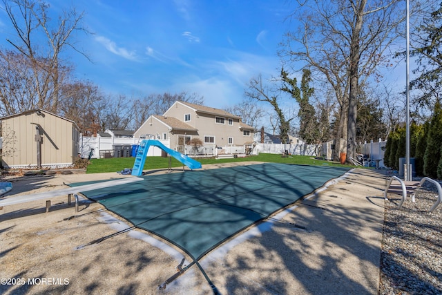 view of pool with a fenced backyard, a storage shed, a water slide, and an outdoor structure