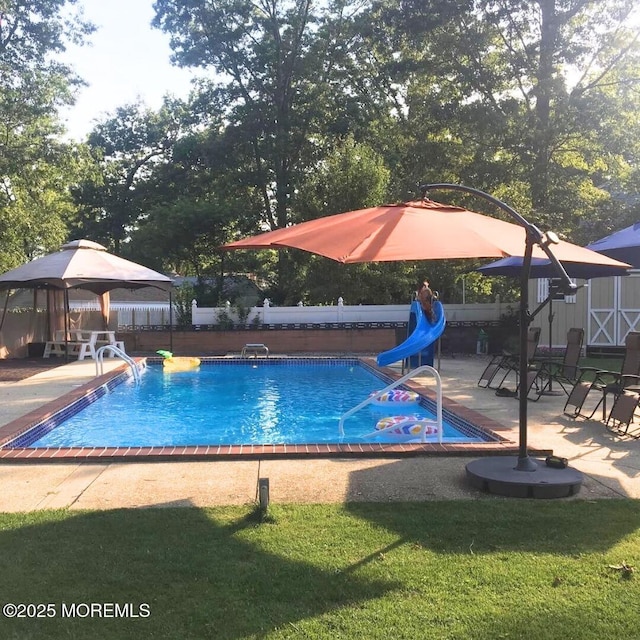 pool featuring fence, a water slide, a yard, a gazebo, and a patio area